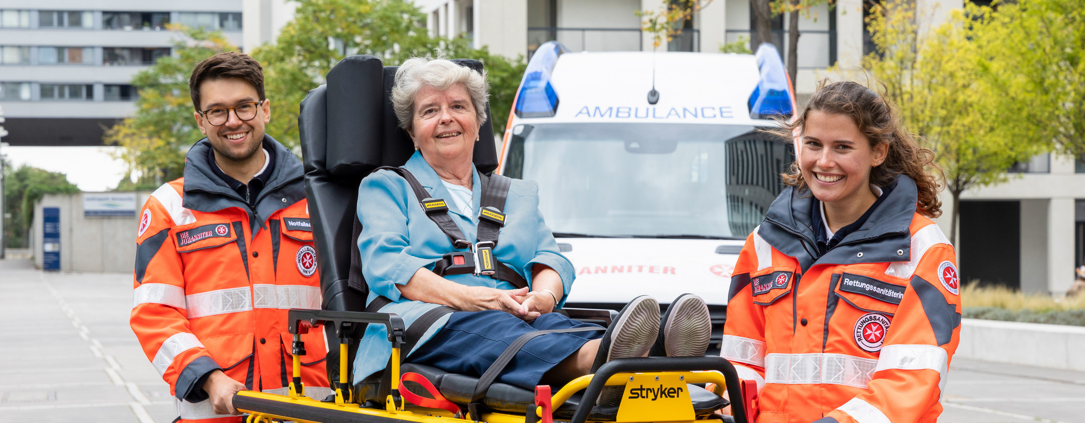 Zwei ehrenamtliche Sanitäter:innen transportieren eine Patientin auf einer Fahrtrage.