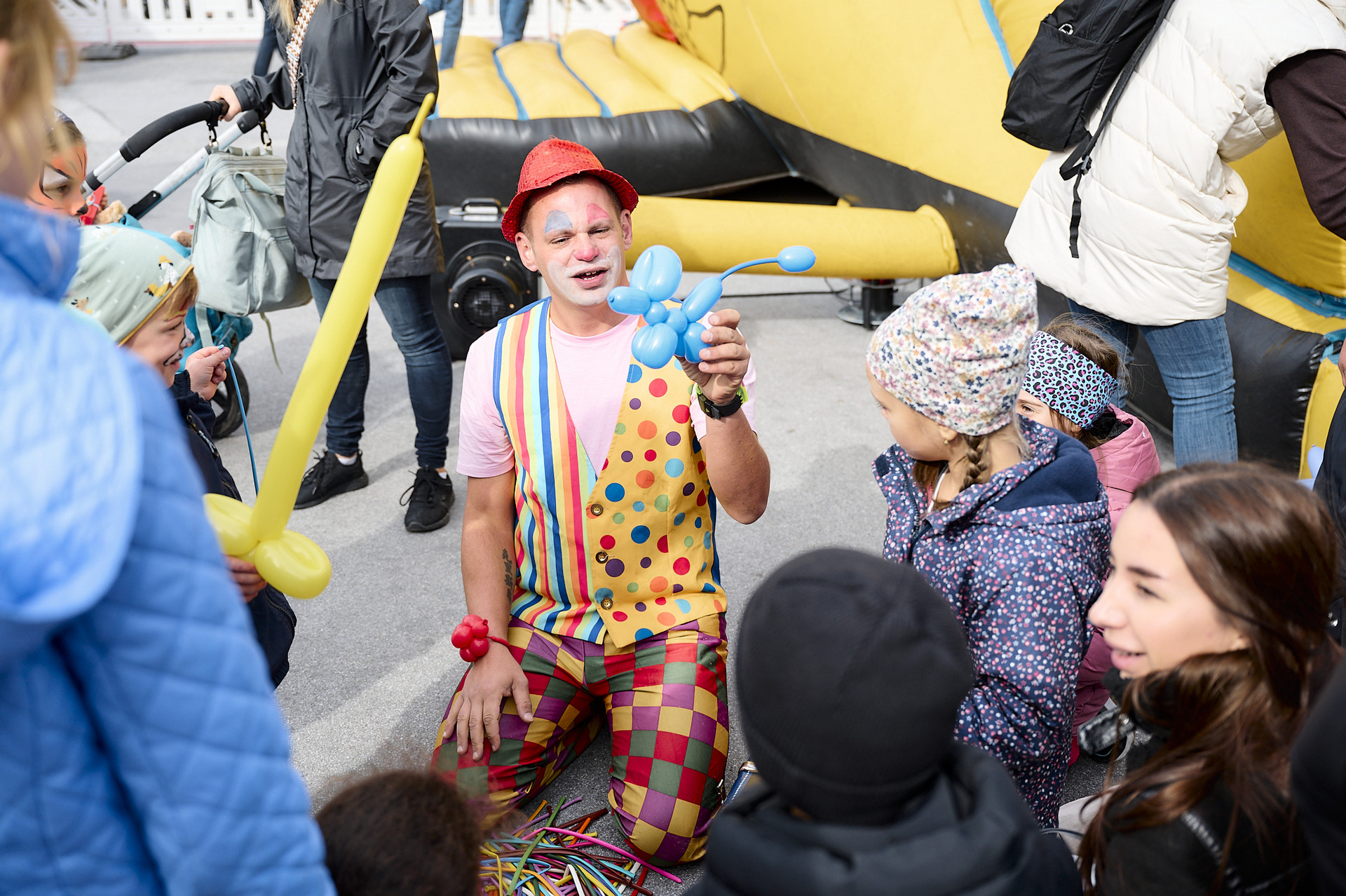 Ein Clown bastelt Luftballontiere für Kinder.